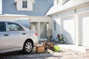 Picnic basket, fishing rod, flippers and bags outside car in driveway